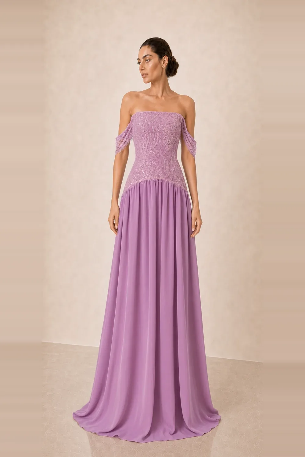 A model wearing the limited-edition Joie Couture gown in lilac, its beaded lace bodice above a gathered chiffon skirt, photographed against a pale ivory studio ground