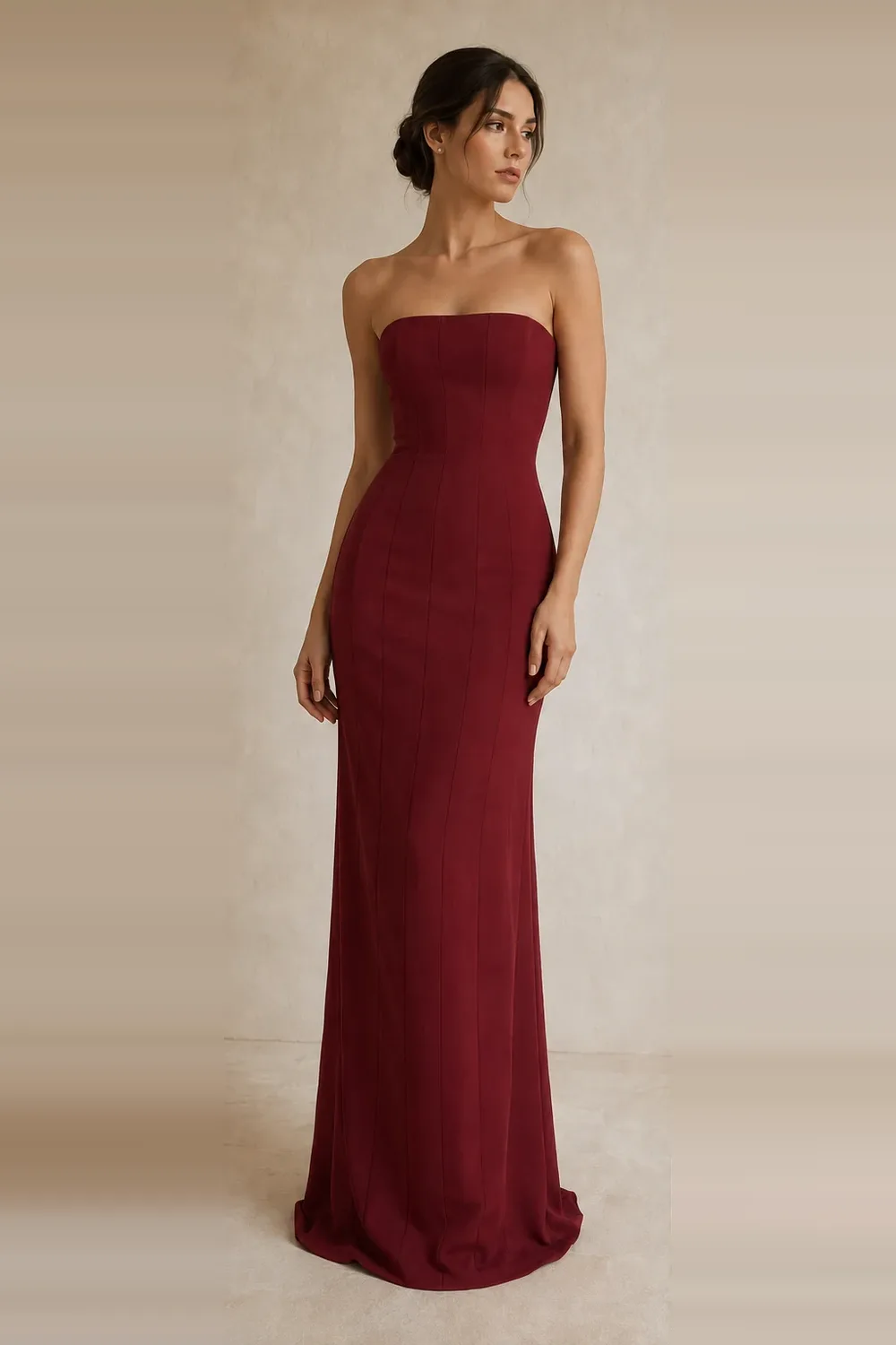 A model wearing the Joie Couture strapless maroon column gown, photographed against a pale ivory studio ground